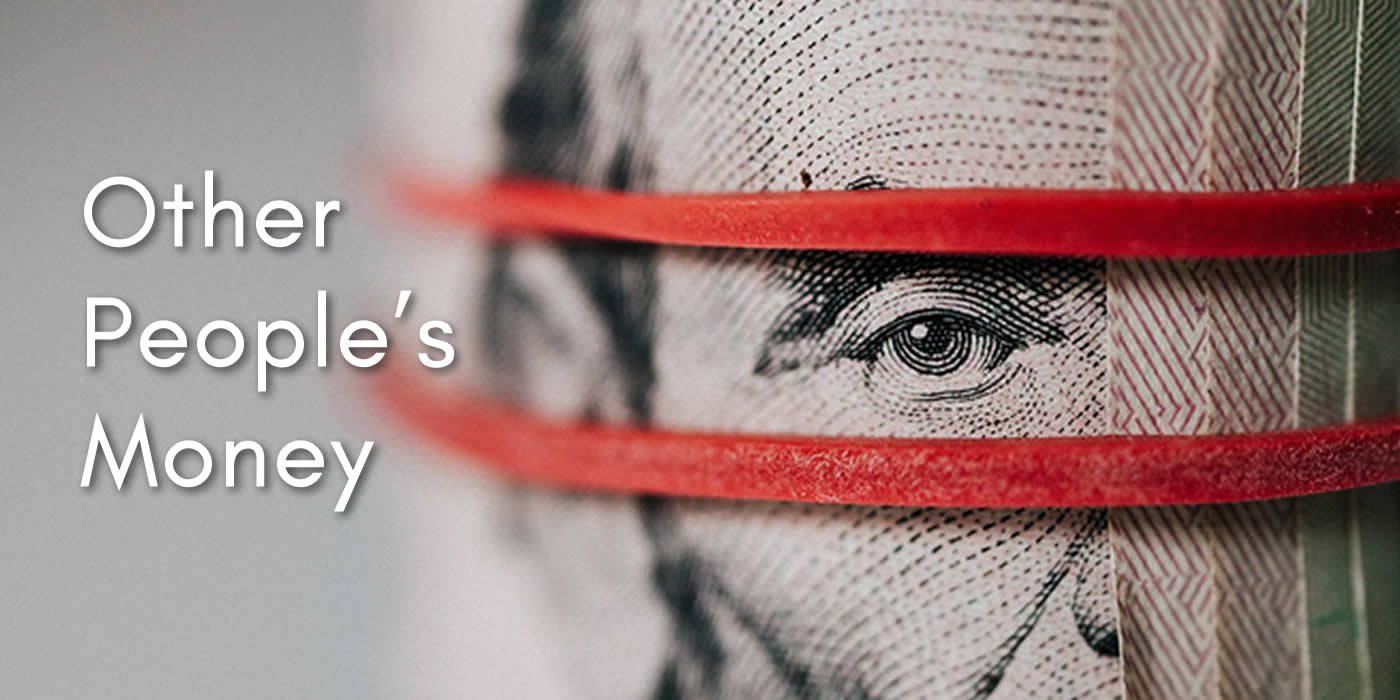 Close up on a roll of 20 dollar bills surrounded by a red rubber band